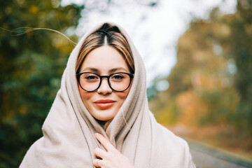 Portrait of beautiful young woman in eyeglasses, enjoying autumn weather in the park. Woman walking in the autumn park.