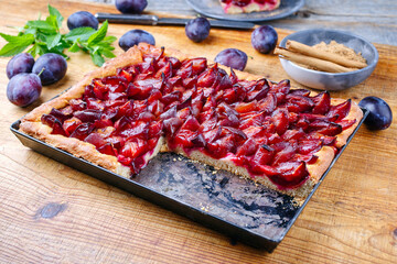 Traditional German Zwetschgenkuchen with sliced plums served as close-up on a rustic backing sheet on a wooden board