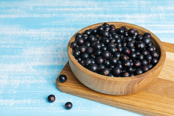 Fresh black currant in wooden bowl on dark table
