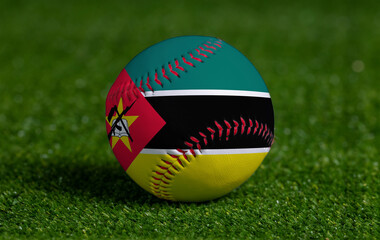 Baseball with Mozambique flag on green grass background, close up