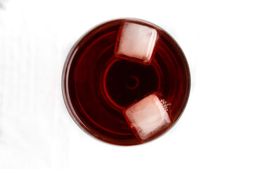 Top view of glass with red lemonade and two ice cubes. White background.