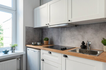 Interior of kitchen with window, wooden furniture and counter with utensils. Modern room in apartment. Scandinavian design.