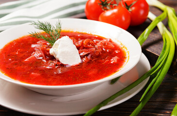russian borscht with sour cream and dill in a white plate,