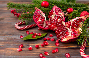 ripe pomegranate , fir branches, Christmas balls, lollipops on a dark brown