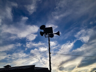 Silhouette of a civil defense siren in the background of the cloudy sky