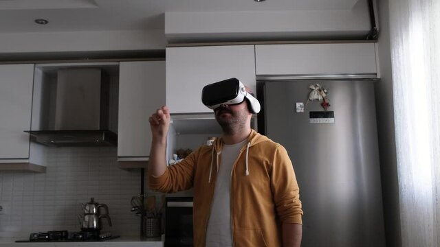 Young man walking around virtual market with vr glasses in kitchen. Young man buying kitchen necessities in the virtual world.