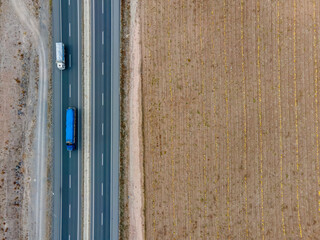 Transport trucks on the highway passing by the cultivated field