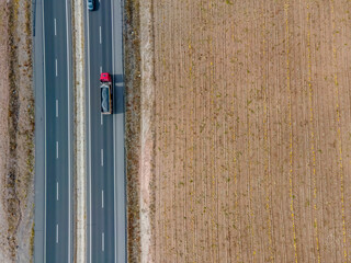 Transport trucks on the highway passing by the cultivated field