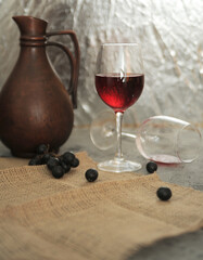 still life georgian jug and wine glasses on linen with a grape on stone background	