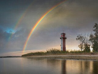 Double rainbow above sea and lighthouse in the morning with calm water