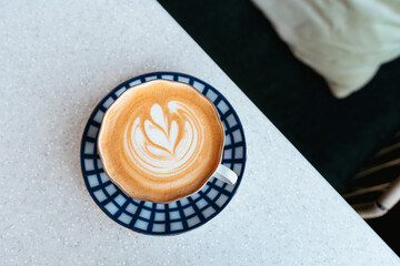 Cappuccino with beautiful foam, blue with white coffee cup top view close-up on white background. Flat lay style. Perfect latte art, top view.