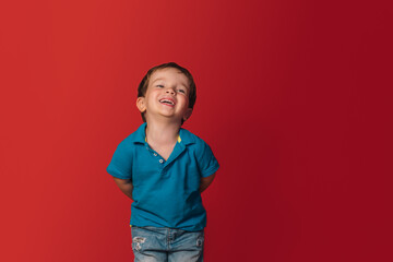 laughing boy in a blue t-shirt on a red background.
