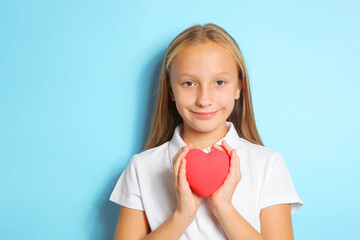 Girl holding a red heart in her hands on a blue background