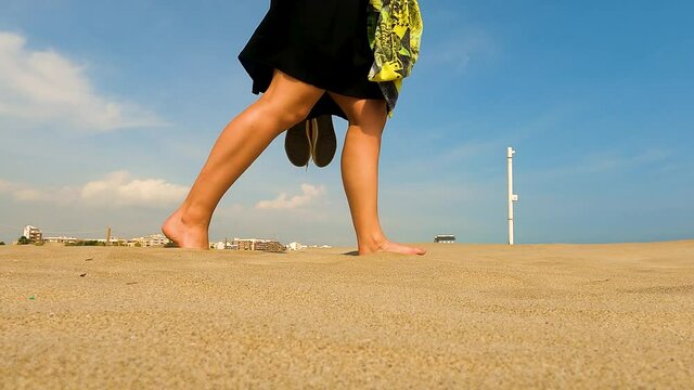 YOUNG BLONDE LADY WALKING BAREFEET IN SAND ON BEAUTIFUL BEACH  IN SPAIN AT COSTA BRAVA