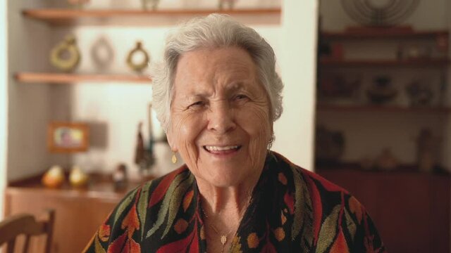 Senior smiling woman in warm shawl in dining room