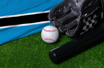 Baseball bat, glove and ball near Botswana flag on green grass background