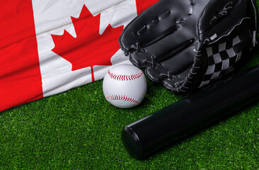 Baseball bat, glove and ball near Canada flag on green grass background