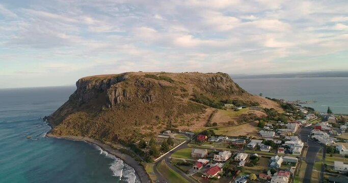 Backward tracking aerial view of the township of Stanley and the ancient volcanic plug know as " The Nut", Stanley, Tasmania, Australia