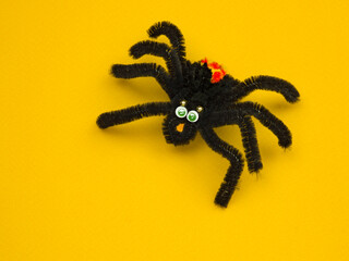funny toy black spider on a yellow background . Halloween