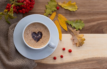 A cup of coffee, with a heart of chocolate on a beautiful autumn phonon. Layout with space for text.