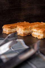 Some caramel sauce snacks with cream and some kitchen's clamps on a black wooden table 