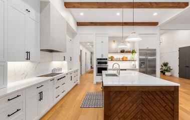 Beautiful white kitchen in new luxury home with large island. Features large island, stainless steel appliances, and sleek modern range hood.