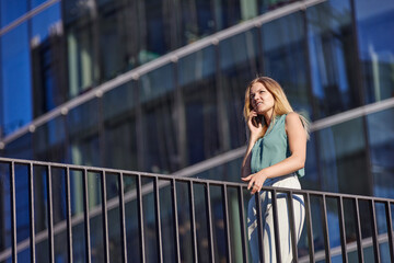 Businesswoman in suit talks by smartphone near business center.