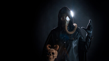 Post-apocalyptic world, concept. A gloomy servant of the devil cult in a black hood and a gas mask...