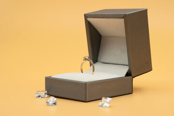 Shiny gold ring in its box on yellow background surrounded by diamonds