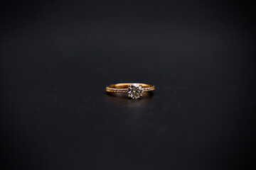gold ring with diamond on black background