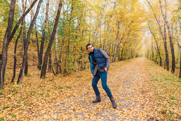 Fototapeta premium Tall handsome man walking in the autumn alley