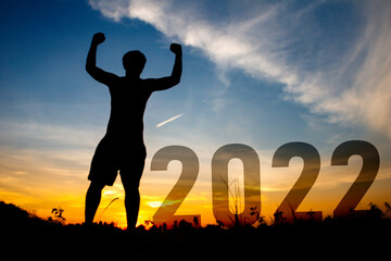 Happy new year and man is show hand Silhouette sunset background.A man standing with 2022 new year.new year,success ,2022,new life.Photo Silhouette and new year  concept idea.