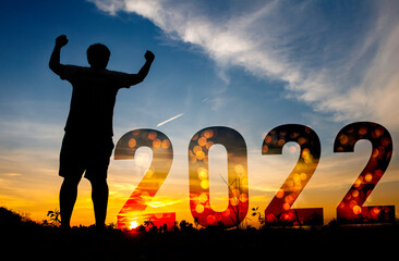 Happy new year and man is show hand Silhouette sunset background.A man standing with 2022 new year.new year,success ,2022,new life.Photo Silhouette and new year  concept idea.
