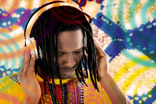 Portrait of a Disc Jockey (DJ) listening to reggae music, dreadlocks, audio headset, colored background, photo, horizontal format