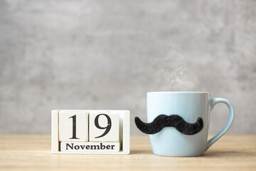 International Men day with November 19 calendar, Blue coffee cup or tea mug and Black mustache decor on table. Happy father day and celebration concept