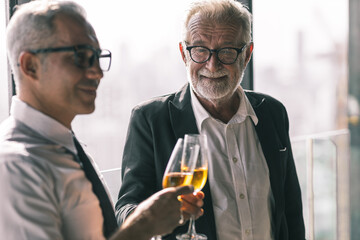 Young business man taking to his older business man partner. They are in white shirt and black tie. They are in a hotel lobby. 