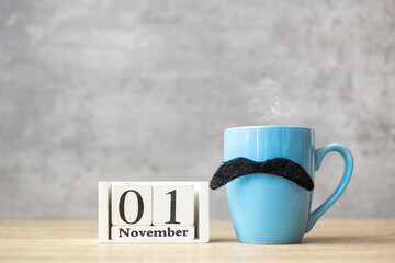 November 1 calendar, Blue coffee cup or tea mug and Black mustache decor on table. Men day, Happy father day and Hello November concept