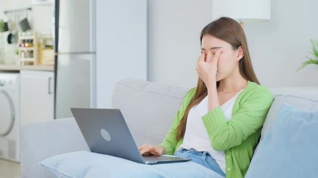 Exhausted Asian business woman hurt eye while using laptop computer.