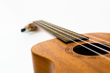 Obraz premium Close up of brown Ukulele on white background. Ukulele strings, saddle, soundhole, ukulele body, neck, fretboard.