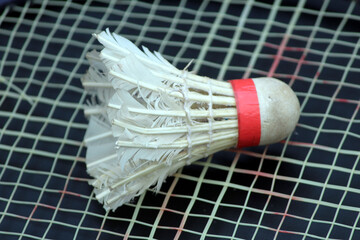 a shuttle cock on a racket with light black background
