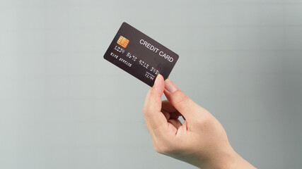 Hand is holding black credit card isolated on grey background.