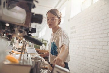 Fototapeta na wymiar Beautiful young woman barista working in coffee shop