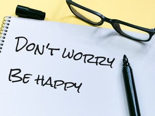 Notebook written do not worry be happy with marker pen an eye glasses.