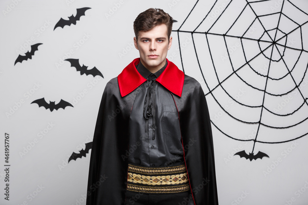 Wall mural Vampire Halloween Concept - Portrait of handsome caucasian Vampire in black and red halloween costume.