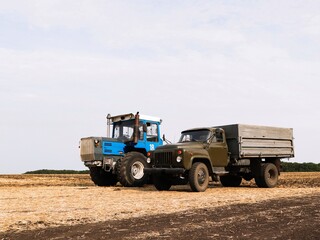 Truck and tractor stand in the field.