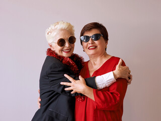 Two beautiful stylish mature senior women in sunglasses hugging. Fun, party, style, celebration...