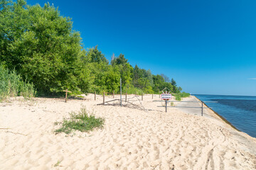 Riverbank of Vistula river near estuary Vistula river to Baltic Sea at summer time with sign Prohibited entry, may result in drowning in Polish language.