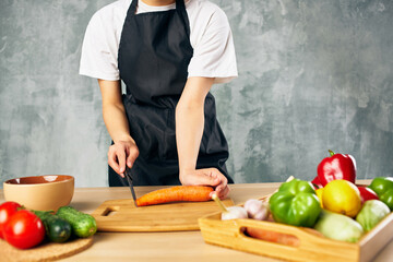 Cook woman on the kitchen cutting vegetables cutting board