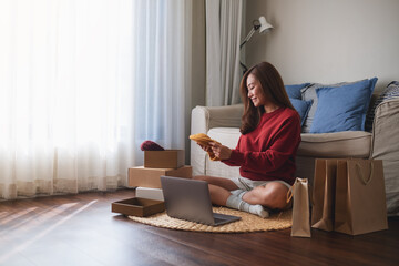 A woman using laptop for online shopping , opening postal parcel box at home