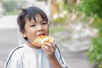 Asian​ child​ boy​ biting and​ eating​ a​ hamburger.​ Fast food.​ Kid​ and​ healthy​ concept.​ 7-8​ years​ old​ of​ childhood.
